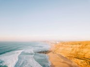 Hermosa vista del dron de agua de mar rodando en la costa arenosa en el día soleado en la naturaleza increíble - foto de stock