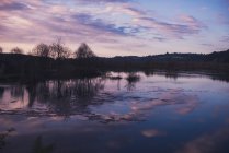 Cielo serale nuvoloso sul lago calmo in campagna — Foto stock
