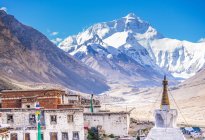 Vue majestueuse sur les vieilles maisons grogneuses et le temple traditionnel contre le pic de montagne enneigé fantastique par une journée ensoleillée au Tibet — Photo de stock