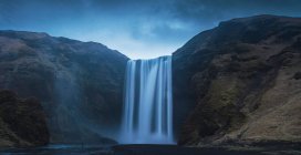 Дивовижний вигляд чудового водоспаду та грубих скель у чудовий хмарний день в Ісландії. — стокове фото