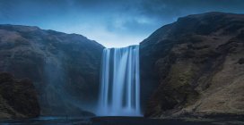 Vista mozzafiato di una magnifica cascata e ruvida scogliera in una bella giornata nuvolosa in Islanda — Foto stock