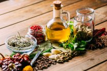 Assorted spices and herbs and bottle of oil placed on wooden tabletop — Stock Photo