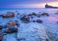 Bright cloudy evening sky over majestic sea and rocky shore — Stock Photo