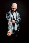 Bearded hairless hipster in shirt with tattoos on arms on black background — Stock Photo