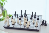 Зверху шахова дошка з білими та чорними фігурами на столі на розмитому фоні — стокове фото