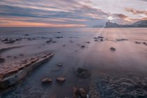 Bella vista del cielo serale nuvoloso luminoso sopra il mare maestoso e la riva rocciosa in una natura spettacolare — Foto stock