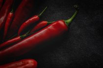 Fresh red spicy chilli peppers on black background — Stock Photo