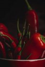 Крупный план свежего красного острого перца чили в чашке на черном фоне — стоковое фото