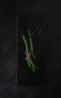 Свіжий зелений гострий перець чилі на сланці на чорному тлі — стокове фото