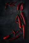 Fresh red spicy chilli peppers scattered on black background — Stock Photo