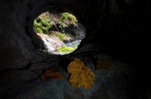 Vista através do buraco na rocha de pequena cachoeira e rochas — Fotografia de Stock