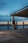 Спортсмен балансує на гімнастичних кільцях на набережній міста — стокове фото