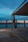 Атлетик балансирует на гимнастических кольцах на набережной в городе — стоковое фото