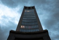 Vista prospectiva de baixo do edifício alto da torre com fachada de pedra e janelas sob céu nublado, Astúrias — Fotografia de Stock