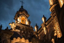 Desde abajo de la catedral de piedra envejecida en luces bajo el cielo oscuro de la noche, España - foto de stock