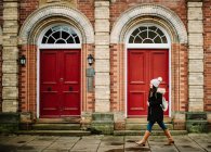 Vue latérale d'une touriste marchant aux portes rouges d'un immeuble en brique dans la rue York, Angleterre — Photo de stock