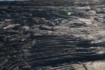 Struttura primo piano di roccia scura ruvida alla luce del sole — Foto stock