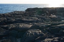 Costa ruvida con rocce squallide a fianco dell'oceano nella giornata di sole — Foto stock