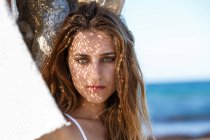 Headshot einer sinnlich attraktiven Frau, die am sonnigen Strand leidenschaftlich in die Kamera blickt — Stockfoto