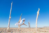 Вид збоку приваблива жінка стрибає з парео на піщаному пляжі в готелі сонячний безхмарний день — стокове фото