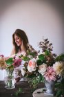 Woman near table with bouquets of blooms in vases — Stock Photo