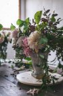 Konzept des Straußes aus trockenen und frischen Rosen, Chrysanthemen und Pflanzenzweigen in Retro-Vase auf Holzbrett auf grauem Hintergrund — Stockfoto