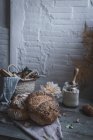 Ramo de ramitas de coníferas secas colgando de la torcedura sobre la mesa con panadería cerca de sillas en la habitación - foto de stock
