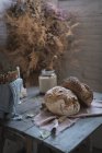 Mazzo di ramoscelli secchi di conifere appesi a torsione sopra il tavolo con panetteria vicino sedie in camera — Foto stock