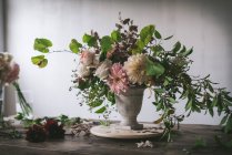 Conceito de buquê de rosas secas e frescas, crisântemos e galhos de plantas em vaso retro sobre tábua de madeira sobre fundo cinzento — Fotografia de Stock