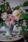 Концепція букета з сухих і свіжих троянд, хризантем і гілочок рослин у ретро вазі на дерев'яній дошці на сірому фоні — стокове фото