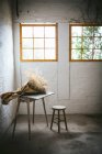 Concetto di mazzo di ramoscelli di conifere secche in carta artigianale su tavolo vicino sgabello in camera di murk grigio con pareti di mattoni — Foto stock