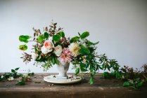 Concetto di bouquet di rose secche e fresche, crisantemi e ramoscelli vegetali in vaso retrò su tavola di legno su fondo grigio — Foto stock
