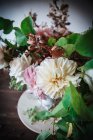 Концепция букета сухих и свежих роз, хризантем и веток растений в ретро-вазе на деревянной доске на сером фоне — стоковое фото
