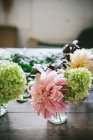 Wooden table with composition of fresh white hydrangea in glasses with water in room on blurred background — Stock Photo