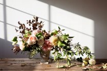 Concept of bouquet of dry and fresh roses, chrysanthemums and plant twigs in retro vase on wooden board on grey background — Stock Photo