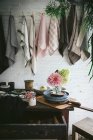Дерев'яний стіл з купою свіжих рожевих хризантем та білою гортензією у вазі між сковородою та посудом біля посуду, що звисає на скручених штифтах — стокове фото