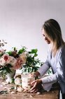 Woman placing plate with cake decorated flower on table with bou — Stock Photo