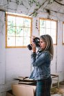 Mujer tomando fotos en la cámara profesional en la habitación - foto de stock