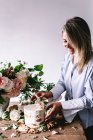 Woman placing plate with cake decorated flower on table with bou — Stock Photo
