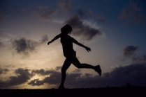 Silhouette of jumping woman on background of sunset sky — Stock Photo
