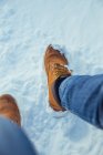 Crop gambe maschili in jeans e stivali invernali seduti sulla neve in giornata di sole vicino alle colline a Cerdanya, Francia — Foto stock