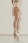 Vista laterale delle gambe del raccolto della signora magra in scarpe da ginnastica in piedi sulle punte dei piedi in stanza luce — Foto stock