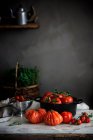 Tomates maduros vermelhos grandes de formas diferentes em panela na mesa perto da parede cinza — Fotografia de Stock