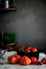 Big red ripe tomatoes of different forms in pot on table near grey wall — Stock Photo