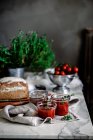 Köstliche frische aromatische Roggenbrot auf Serviette in der Nähe von Messer und Dosen mit Tomaten hausgemachte Marmelade auf verschwommenem Hintergrund — Stockfoto