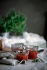 Köstliche frische aromatische Roggenbrot auf Serviette in der Nähe von Messer und Dosen mit Tomaten hausgemachte Marmelade auf verschwommenem Hintergrund — Stockfoto