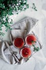 Vista superior de pequenos frascos com deliciosos tomates frescos compota caseira perto de ervas e guardanapo na mesa no fundo borrado — Fotografia de Stock