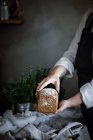 Manos de mujer de la cosecha sosteniendo un delicioso pan de centeno aromático fresco sobre fondo borroso - foto de stock
