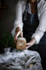 Manos de mujer de la cosecha sosteniendo un delicioso pan de centeno aromático fresco sobre fondo borroso - foto de stock