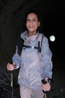 Donna felice con bastoni da trekking in tunnel buio — Foto stock